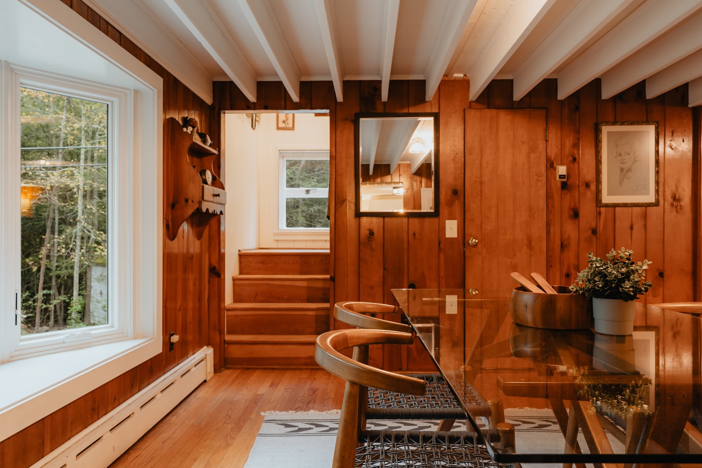 Dining table with chairs near a window overlooking trees.