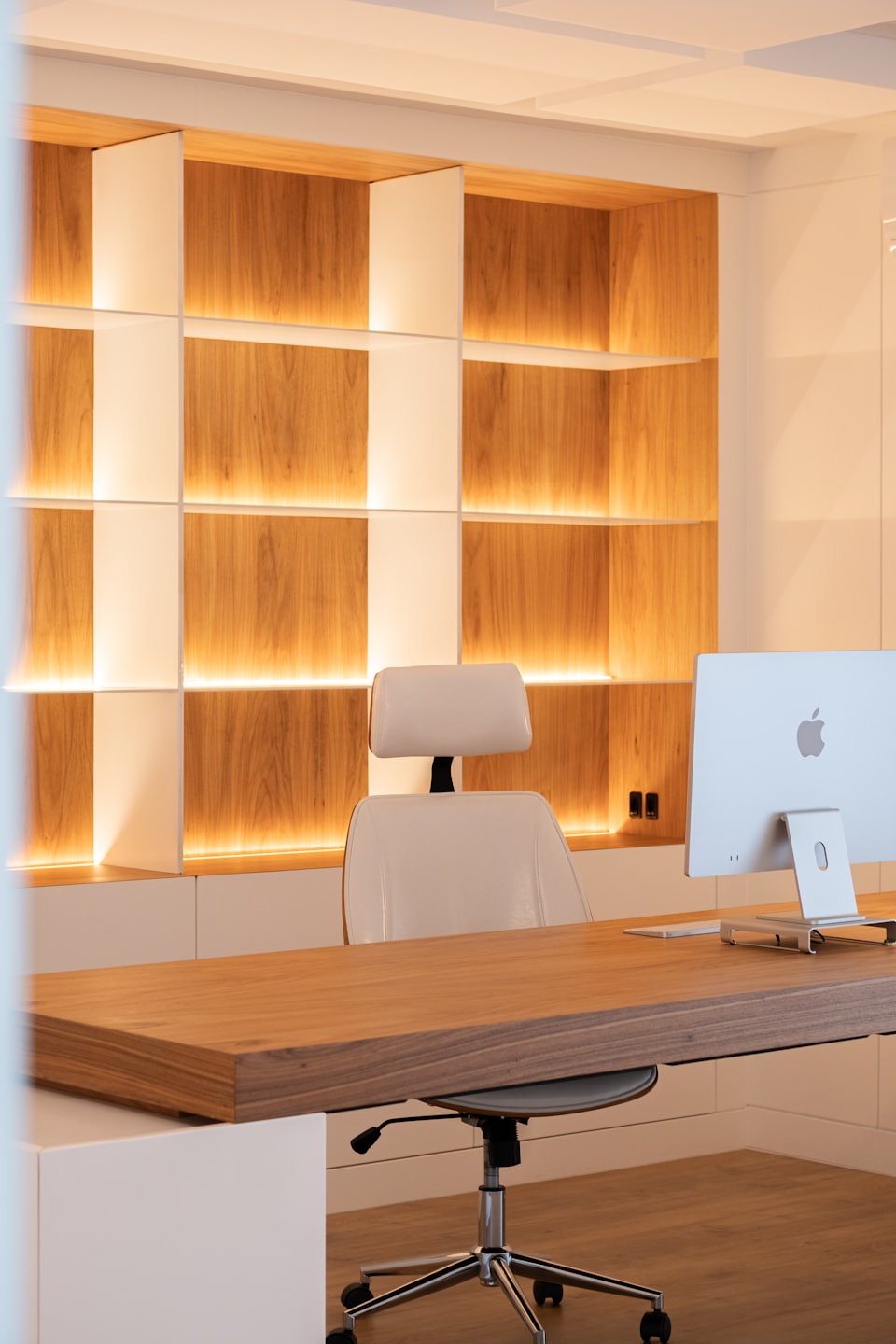 Empty ergonomic office chair at a wooden desk.