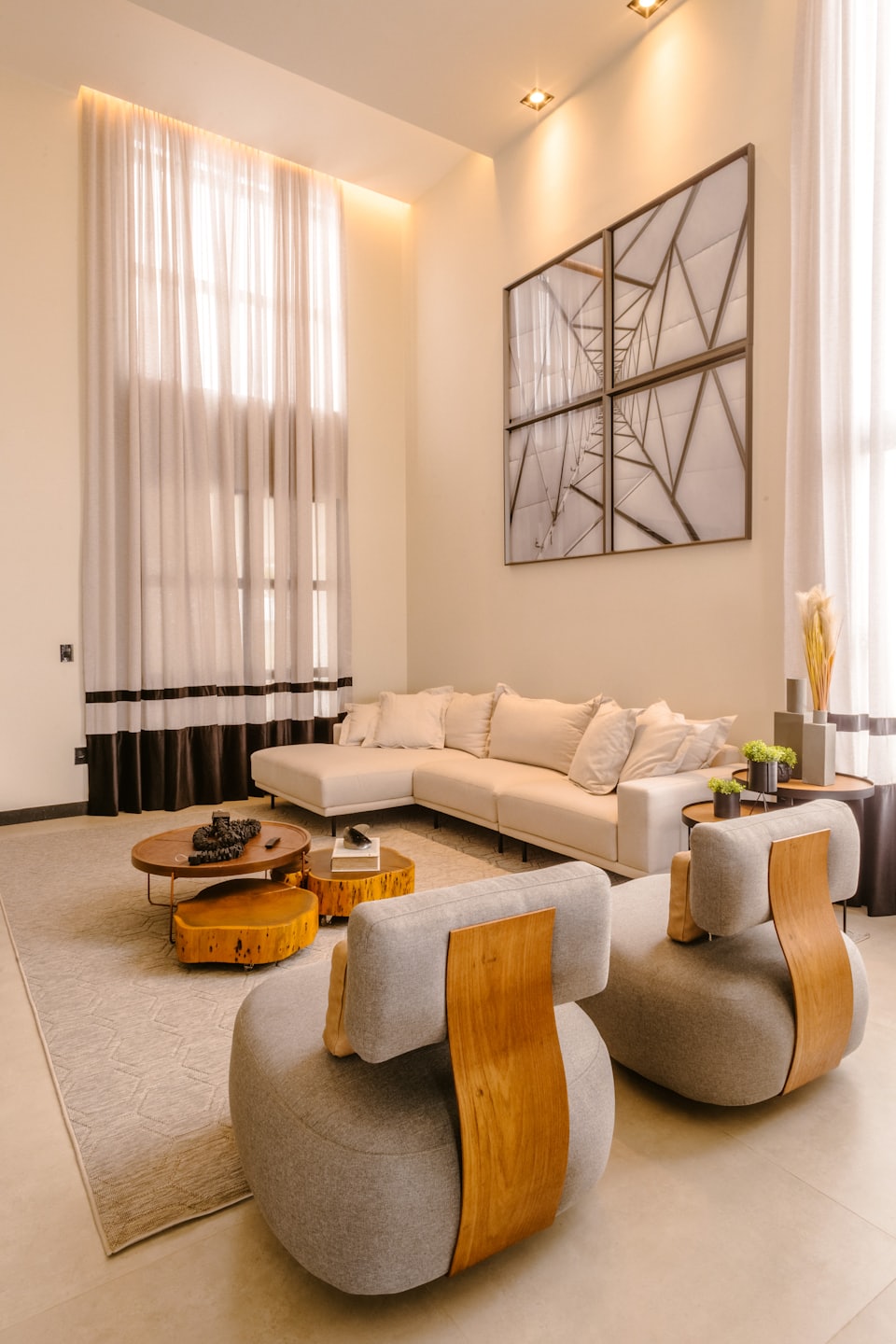 Modern living room with cream L-shaped sofa and grey armchairs.