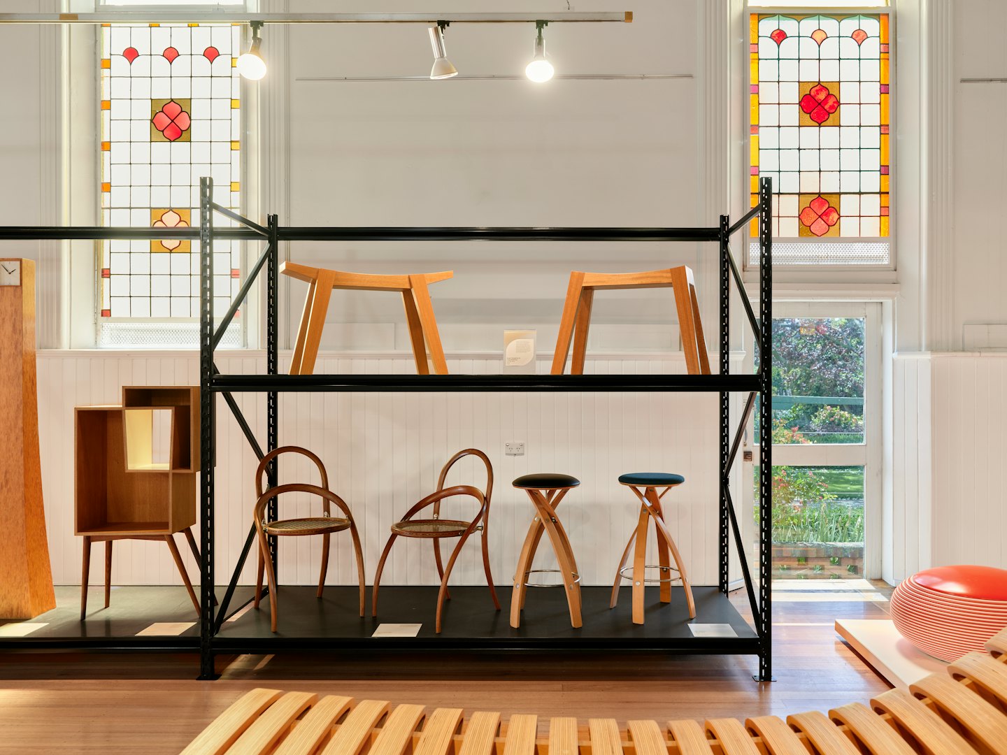 Modern wooden furniture arranged on industrial shelving in a showroom.