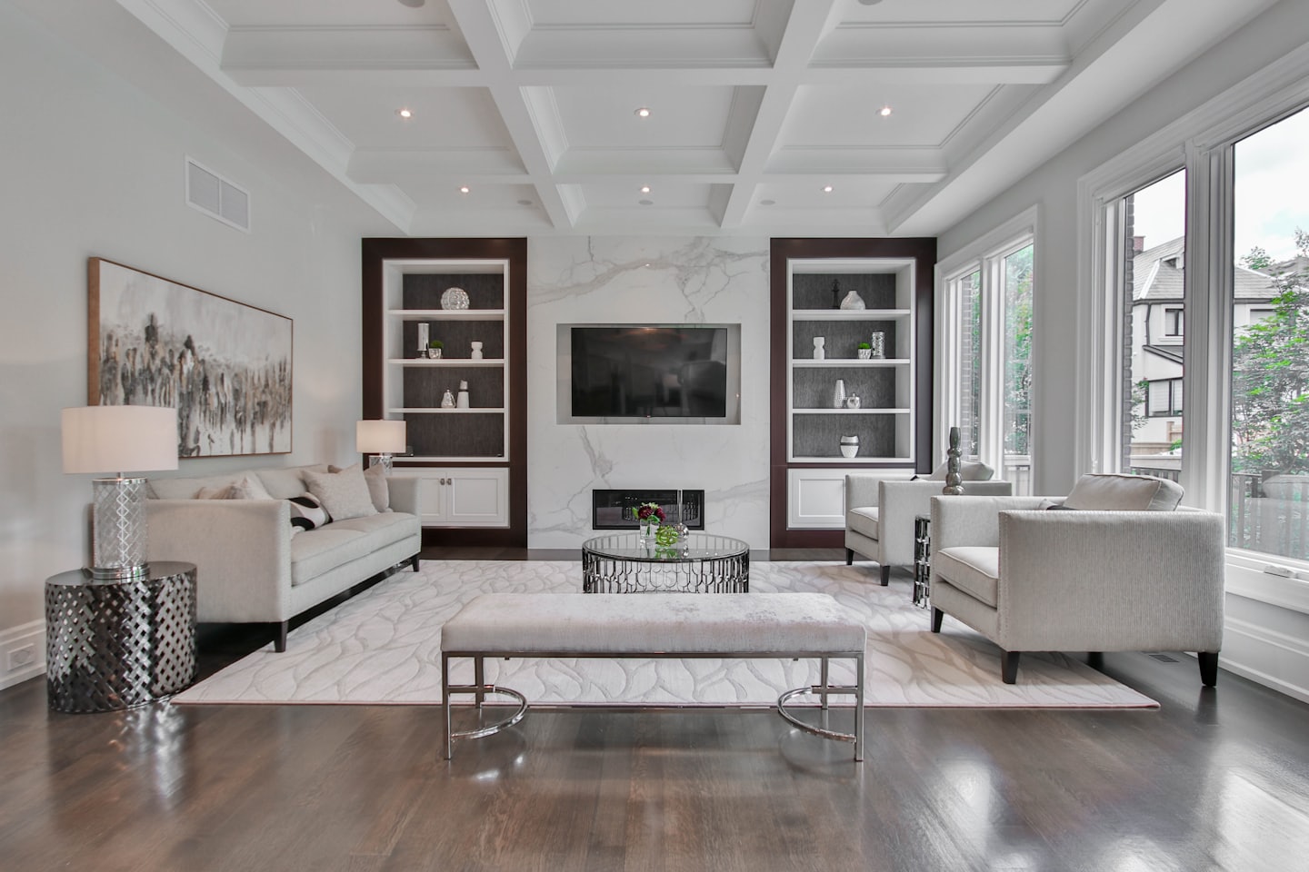 Modern living room with light furniture and TV over fireplace.